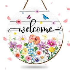 a welcome sign hanging from a rope with flowers and butterflies around it on a white background