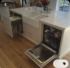 an open dishwasher sitting in the middle of a kitchen next to a sink