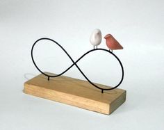 two small birds sitting on top of a wooden stand with an infinite sign in the middle