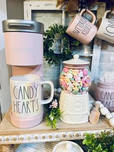 coffee mugs and candy hearts are sitting on a shelf