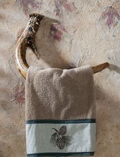 a towel hanging on the wall next to a wooden hook with a pineapple embroidered on it