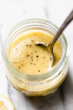 a glass jar filled with mustard sitting on top of a table next to sliced lemons