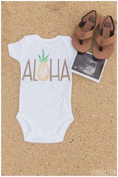 a baby's bodysuit and sandals are laying on the sand