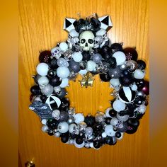 a wreath with skulls and other decorations hanging on the front door is decorated with black, white and silver balls