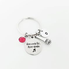 a silver keychain with music notes on it and a red ball in the middle