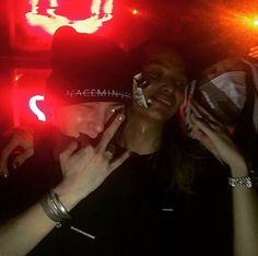 two people standing next to each other in front of a neon sign with the word peace on it