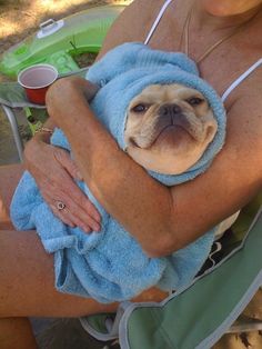 a woman holding a dog wrapped in a towel