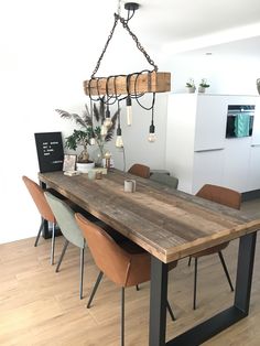 a dining room table with chairs and a light fixture hanging from it's ceiling