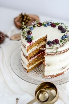 a slice is taken out of a cake with white frosting and berries on top