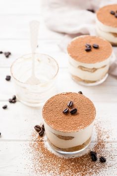 three desserts are sitting on a white table with coffee beans scattered around the top