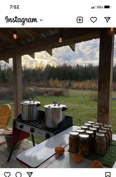 an outdoor cooking area with pots and pans on the grill, next to some pumpkins