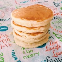 a stack of pancakes sitting on top of a table covered in colorful paper with words all over it