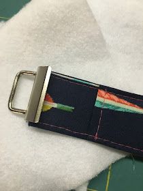 a belt with a metal buckle on it sitting on top of a piece of fabric