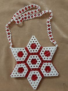 a red and white beaded star ornament on a brown cloth with beads