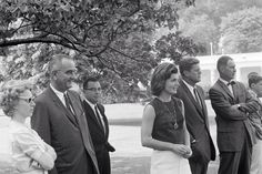 a group of people standing next to each other in front of a tree and building