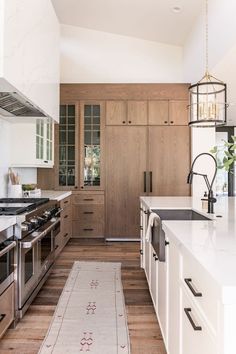 a kitchen with white counter tops and wooden cabinets, along with an area rug on the floor