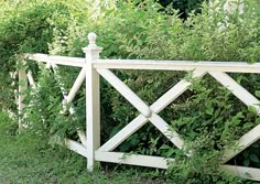 a white wooden fence surrounded by green bushes