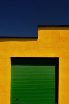 a yellow building with a green garage door