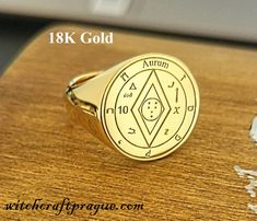 a gold ring with an astro sign on the front and side, sitting on top of a wooden table