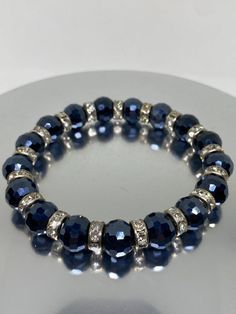 Add a touch of elegance to your wrist with this stunning bracelet. The piece features navy blue glass beads and genuine crystals that will add a pop of sparkle to any outfit. The bracelet is stretchable, making it easy to slip on and off, and it has a beaded design that adds a unique touch to the overall look. This bracelet is perfect for any occasion, whether it's a special event like a wedding or graduation, or an everyday accessory. The piece is 7 inches in length and has a silver base metal with an unknown metal purity. The bracelet is not only beautiful, but it also makes a great gift for Mother's Day, Christmas, Valentine's Day, or any other special occasion. Blue Glass Beaded Bracelets For Gift, Elegant Blue Crystal Bracelet With Polished Beads, Elegant Blue Glass Bracelets, Blue Glass Stretch Bracelet With Round Beads, Elegant Blue Beaded Nickel-free Bracelets, Everyday Accessories, Mother Day Gifts, Blue Glass, Special Events