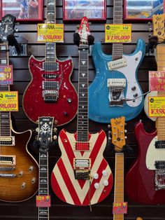 guitars are on display in a store with red, yellow and blue ones hanging from the wall