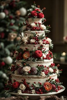 a christmas cake decorated with red and white flowers on a table next to a christmas tree