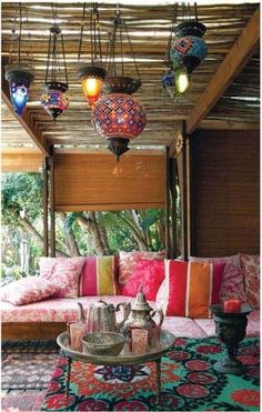 a living room filled with lots of furniture and lamps hanging from the ceiling above it