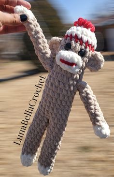 a hand holding up a knitted sock monkey