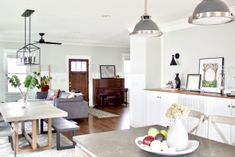 an open concept living and dining room with white walls, wood flooring and large windows