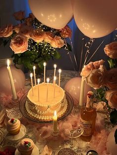 a table topped with a cake covered in frosting and lots of candles next to balloons