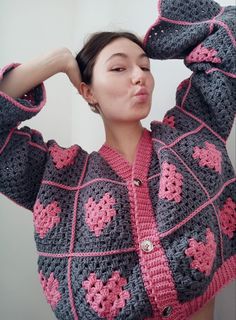 a woman is wearing a crocheted jacket with pink and gray flowers on it