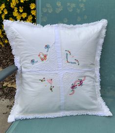 a white pillow sitting on top of a blue chair next to yellow and green flowers