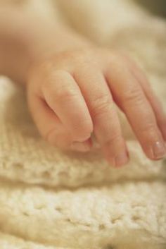 a baby's hand on top of a white blanket