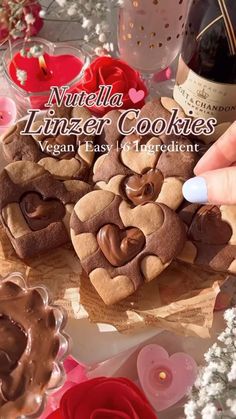 a person is decorating cookies on a table with flowers and wine bottles in the background