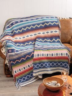 a couch with a blanket on it next to a wooden table and chair in a room