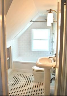 an attic bathroom with black and white floor tiles