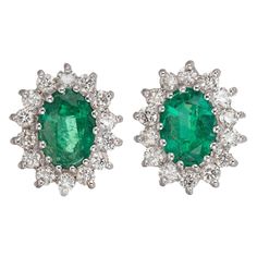 Green oval emeralds with a halo of round full cut diamonds, in 18k white gold. 28 round full cut diamonds, approx. total weight .56cts, G, VS 2 oval top fine bright gem green oval Emeralds 7 x 5mm, approx. total weight 1.75cts 18k White Gold Tested and stamped: 18k 750 2.8 grams Depth: 4mm Width: .39 inch or 10mm Top to bottom: 11.4mm or .45 inch Emerald And Diamond Earrings, Diamond Halo Earrings, Halo Diamond Earrings, Vintage Stud Earrings, Gold Diamond Earrings Studs, Gold Diamond Studs, Round Diamond Setting, Green Oval, Halo Earrings