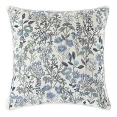 a blue and white floral pillow on a white background with black leaves, branches and flowers