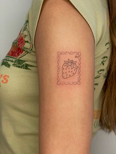 a woman's arm with a small strawberry tattoo on the left side of her arm