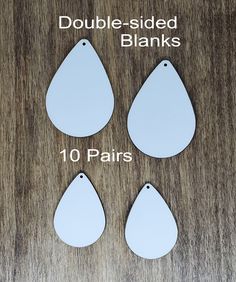 four tear shaped blank tags are shown on a wooden surface with the text double - sided blanks 10 pairs