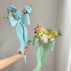 a person holding a bouquet of flowers in front of a window with the ribbon tied around it