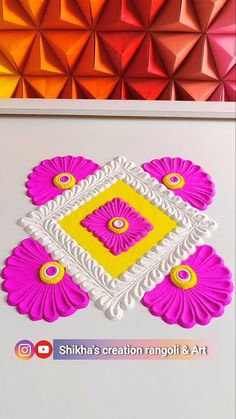 colorful paper work on the wall in front of an orange and pink background with geometric shapes