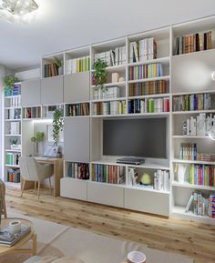 a living room filled with lots of white furniture and bookshelves full of books