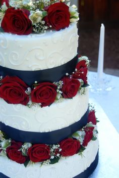 three tiered wedding cake with red roses on top