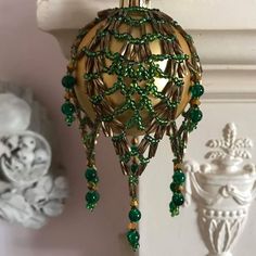 a green beaded ornament hanging from a wall