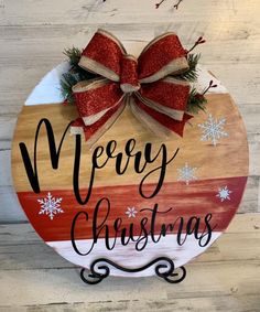 a wooden sign that says merry christmas with snowflakes on it and a bow