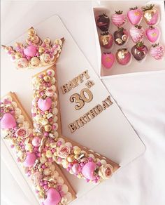 a cake shaped like the letter k with pink frosting and decorations on it, sitting next to a card that says happy 30th birthday