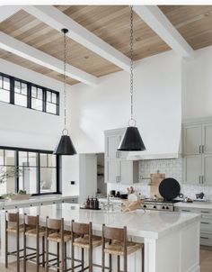 a large kitchen with white cabinets and wooden ceiling beams is pictured in this image, there are four stools at the center of the island