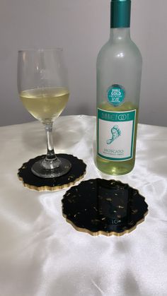 a bottle of wine sitting next to a glass on top of a white table cloth