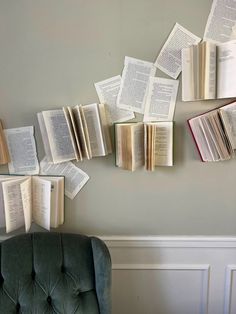 several open books are hanging on the wall above a green chair with a gray back